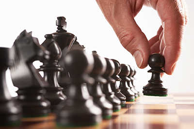 A hand moves a black pawn on a chessboard.