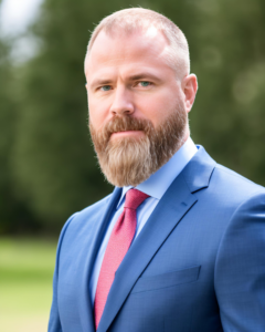A man with a groomed beard wearing a blue suit and a red tie.